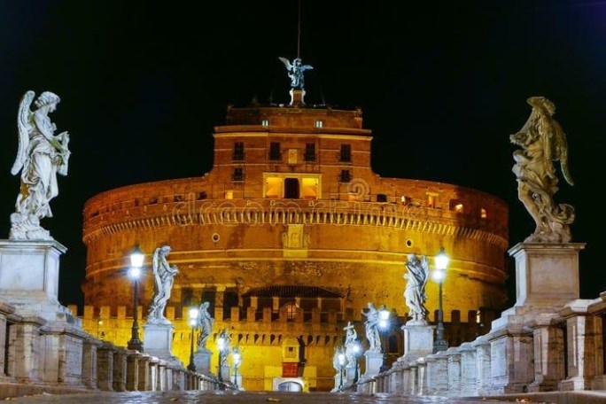 Night view of Castel Sant'Angelo with angel statues on a bridge in Rome.