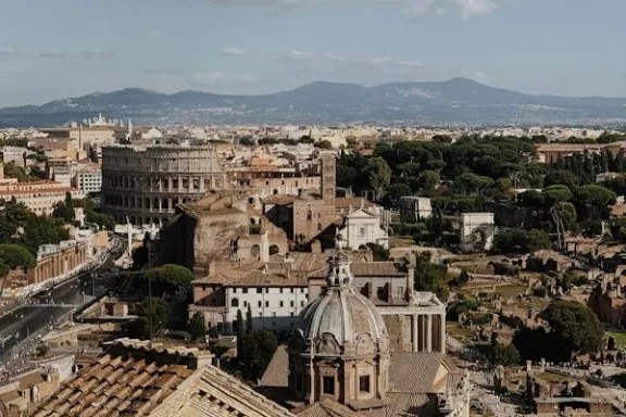 Aerial view of Rome with the Colosseum and ancient ruins under a clear sky.